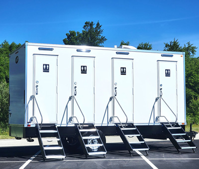 An Exterior view of a Lang 4 Station Eco Series Restroom Trailer under a blue sky.